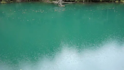 Rain drops falling in to a little nice turquoise lake Stock Footage 218573406