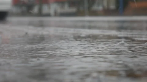 Rain drops falling on a puddle on a car road. 스톡 동영상 128200036