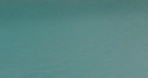 Rain drops falling into torquoise water in slow motion Stock Footage 150643325