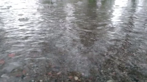 Rain drops falling into a water puddle with water splashing and bubbles Stock Footage 154612223