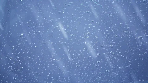 Rain drops falling onto wind shield glass in slow motion Stock Footage 104061360