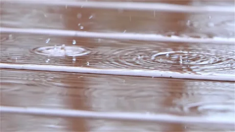 Rain drops falling on the wood plank floor of an exterior deck Stock Footage 146042537