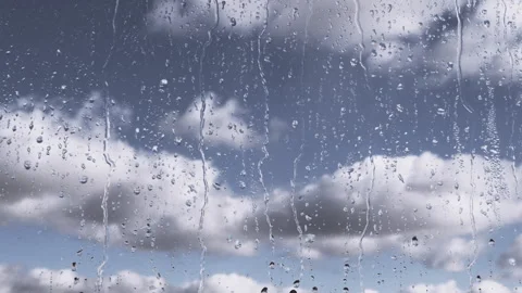 Rain Drops Flow Down Glass Against a Background of Moving Clouds and Grey Sky Video stock 229798633