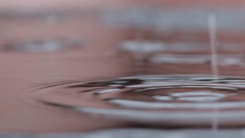 Rain drops hits the floor and makes circles in the evening. Closeup shot Stock Footage 138446908