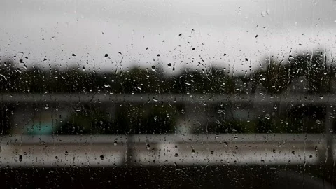 Rain drops rolling down a window on a hotel balcony, on a cloudy rainy bad we Stock Footage 196906893