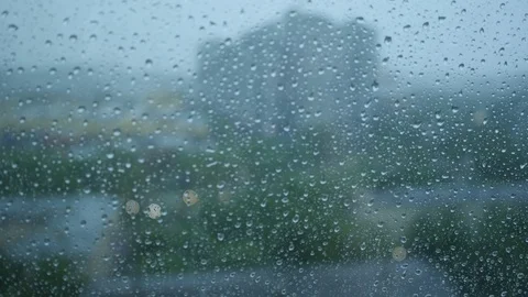 Rain drops run down on a window glass. Bad weather in a city. Close up Видео 121723923
