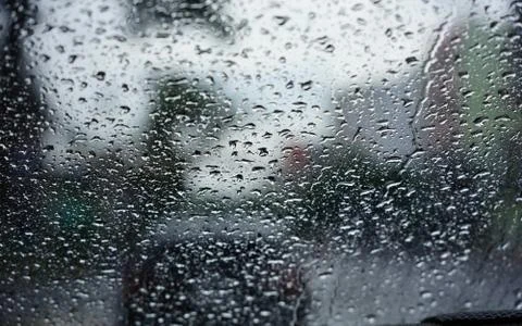 The rain drops seen through the windshield during the evening Stock Photos
