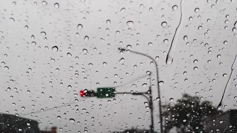 Rain Drops Sliding Down Car Windshield with Blurred Red Traffic Light Stock Footage 343429903