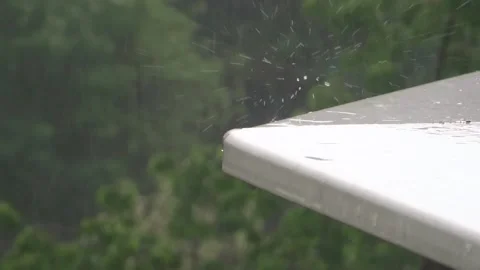 Rain drops splash on a white ledge with trees as background Stock Footage 150825826