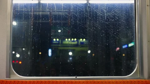 Rain drops on train window at night while driving, urban area lights bokeh .. Stock Footage 339409505