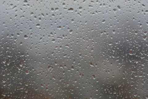 Rain drops on window, against blurry background of a town Stock Photos