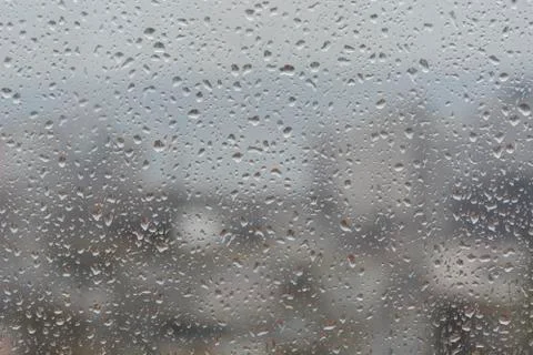 Rain drops on window, against blurry background of a town Stock-Fotos