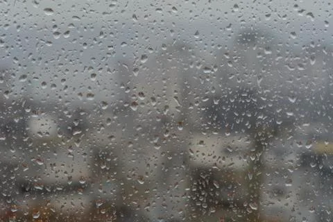Rain drops on window, against blurry background of a town Stock Photos