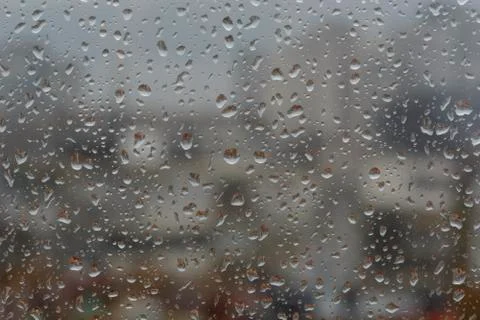 Rain drops on window, against blurry background of a town Stock Photos