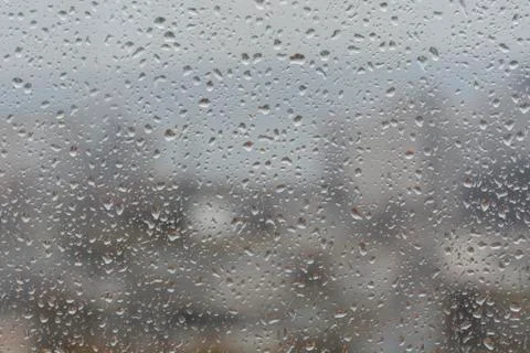 Rain drops on window, against blurry background of a town 스톡 사진