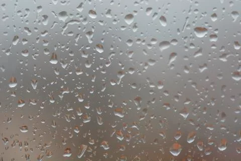 Rain drops on window, against blurry background of a town Stock Photos
