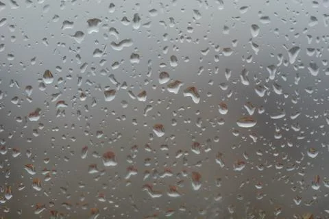 Rain drops on window, against blurry background of a town Stock Photos