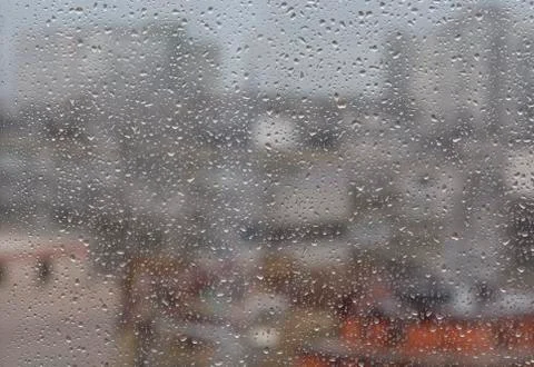 Rain drops on window, againt blurry background of a town Stock Photos