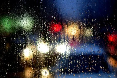 Rain drops on window and blurred traffic lights background Stock Photos