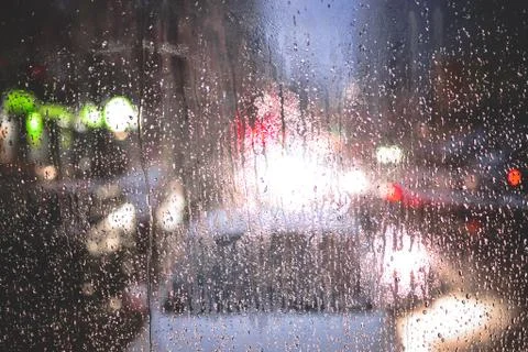 Rain drops on window and blurred traffic lights background Stock Photos