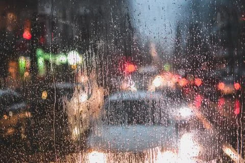 Rain drops on window and blurred traffic lights background Stock Photos