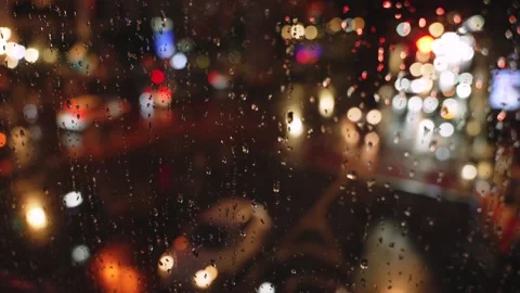 Rain drops on window with blurred city traffic lights at night creating Stock Footage 319007759