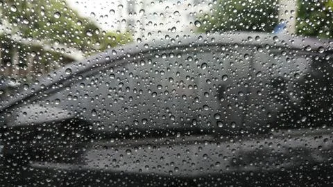 Rain drops on window with car background. Stock Photos