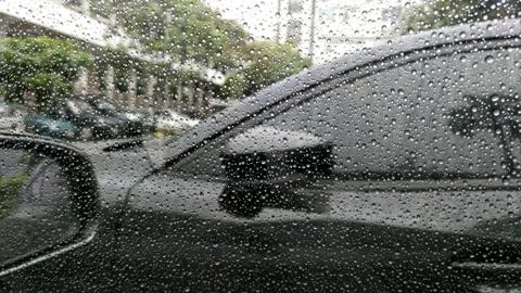 Rain drops on window with car background. Stock Photos