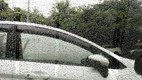 Rain drops on window with car background. Stock Photos
