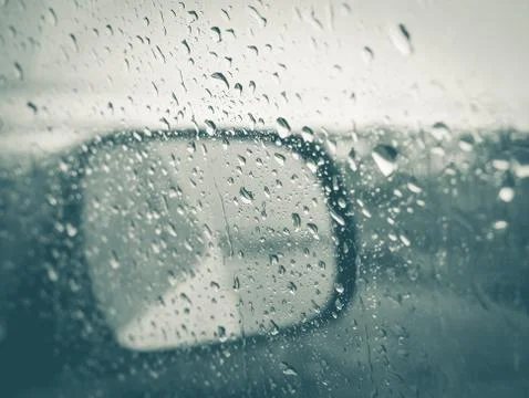 Rain drops on window of car with side-mirror on outside Stock Photos