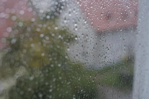 Rain drops on window glass blurred houses with red roofs summer rain storm Stock Photos