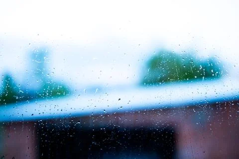 Rain drops on window glass with blurred outdoor background showing building Stock Photos