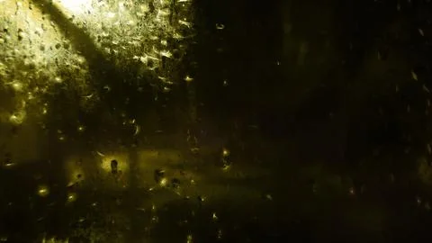 Rain drops on window glass at night create dark abstract texture. Stock Photos