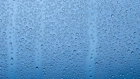 Rain drops on a window glass surface with a blue background texture Fotos de archivo