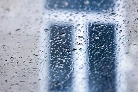 Rain drops on window glasses surface with windows background Stock Photos
