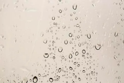 Rain drops on window glasses surface with cloudy background . Stock Photos