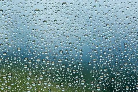 Rain drops on window glasses surface with cloudy background . Stock Photos