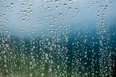 Rain drops on window glasses surface with cloudy background . Stock Photos