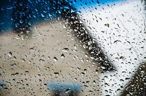 Rain drops on window glasses surface with cloudy background Stock Photos