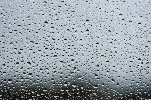 Rain drops on window with grey textured background. Stock Photos