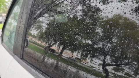 Rain drops on window with moving street view and trees outside rainy day urban s Stock Footage 331347322