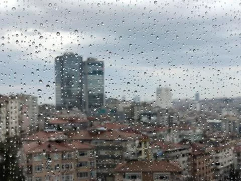 Rain drops on window pane against city view Stock Photos