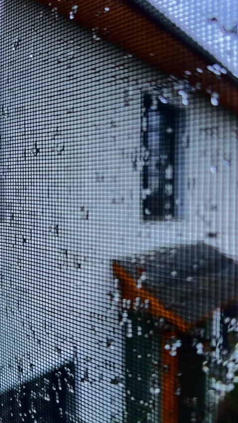 Rain drops on a window protective mesh. Sad mood when staying indoors in rain Stock Footage 318729536
