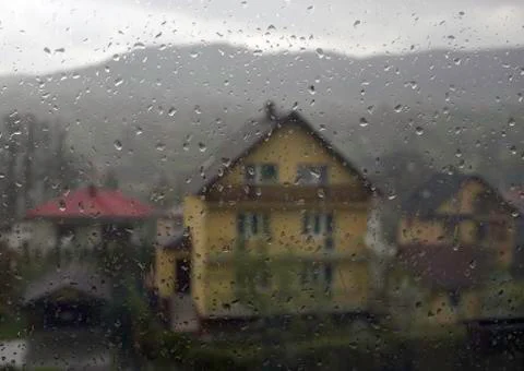 Rain drops on window through a house located in small country side town named Stock Photos