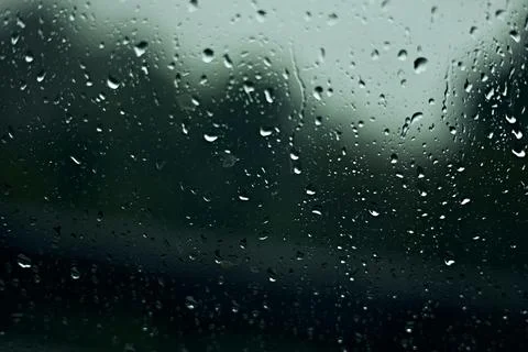 Rain drops on window, with trees and leaves outside. Stock Photos