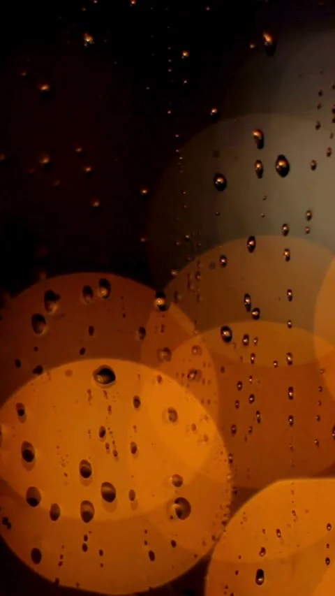 Rain drops on window with warm bokeh lights background Video stock 334169615