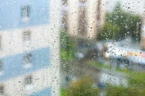 Rain drops on windowpane and blurred city Stock Photos