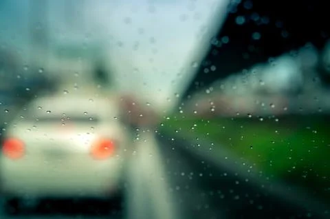 Rain drops on windshield. Car driving on asphalt road on rainy day. Windshiel 库存照片