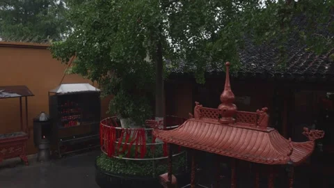 Rain Falling on Ancient Asian Buddhist Temple Courtyard with Red Prayer Ribbons Stock Footage 339375709