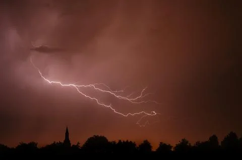 Rain falling and stroke of forked lightning during thunderstorm at night over Fotos Stock